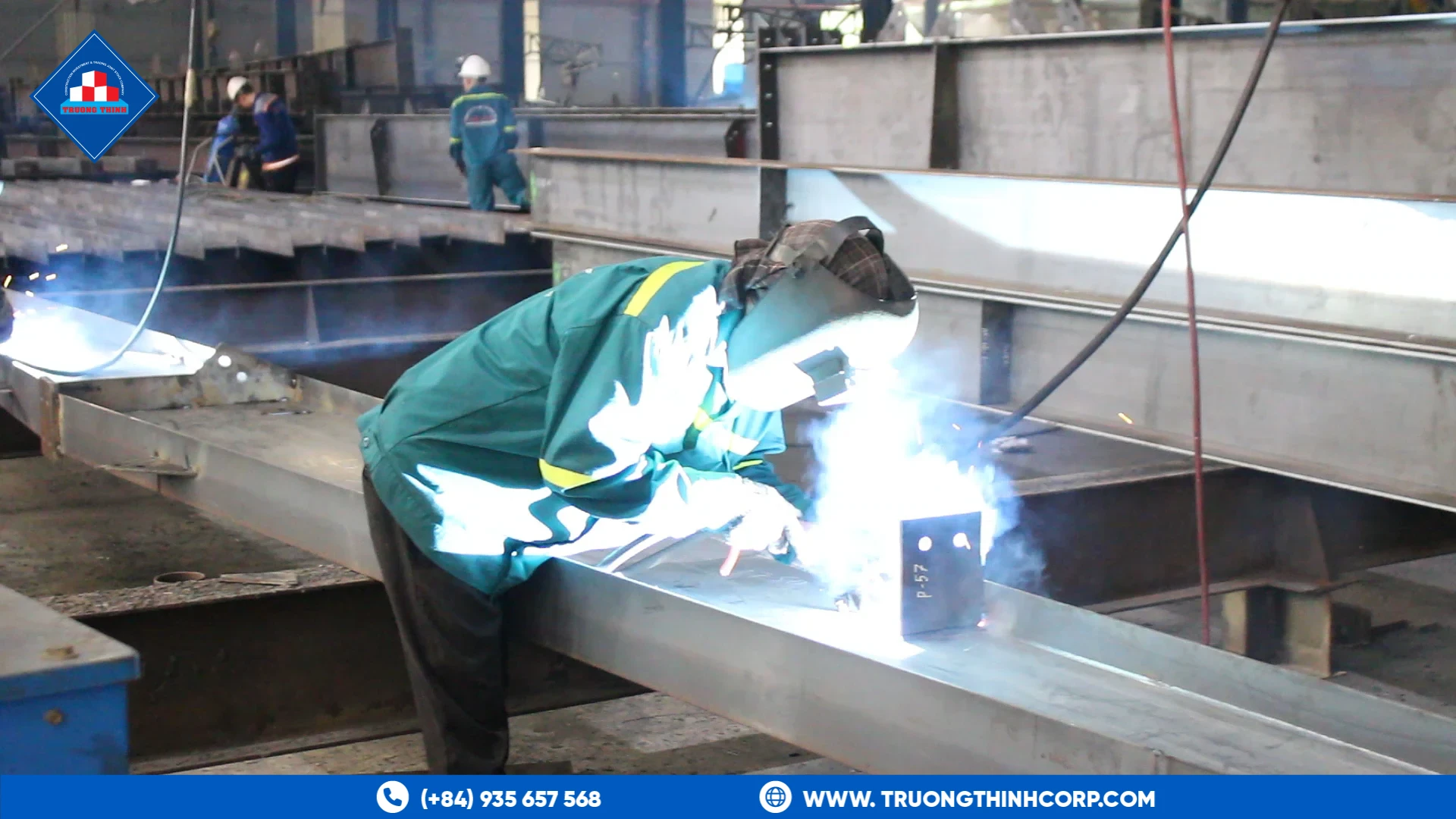 Welder joining a steel column section with base plate at Truong Thinh Corp's fabrication factory