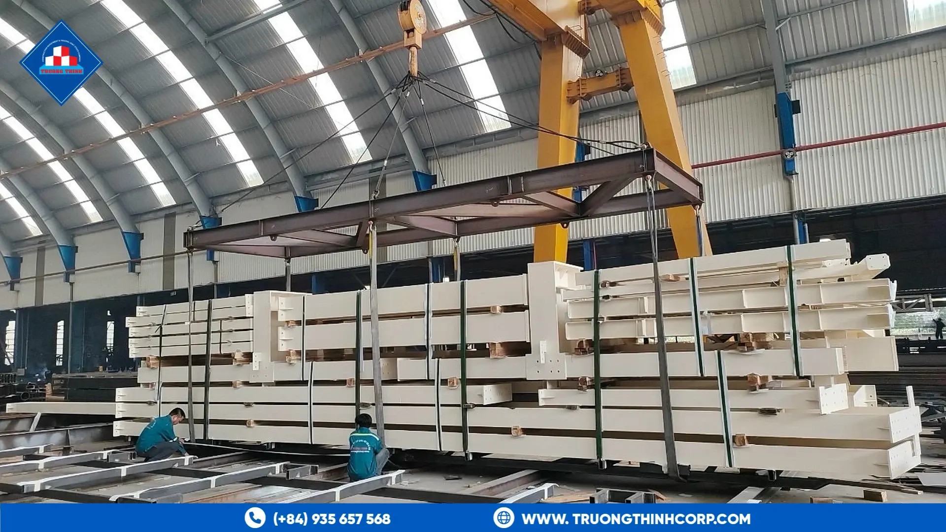 Fabricated white steel sections laid out under a gantry crane at Truong Thinh Corp's factory