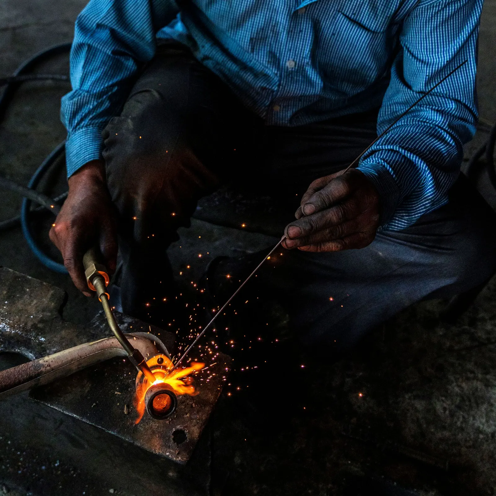 Close-up of a welder joining a steel pipe with visible sparks