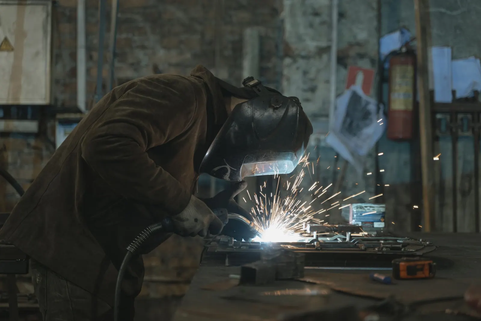 Welder joining metal components in a fabrication workshop