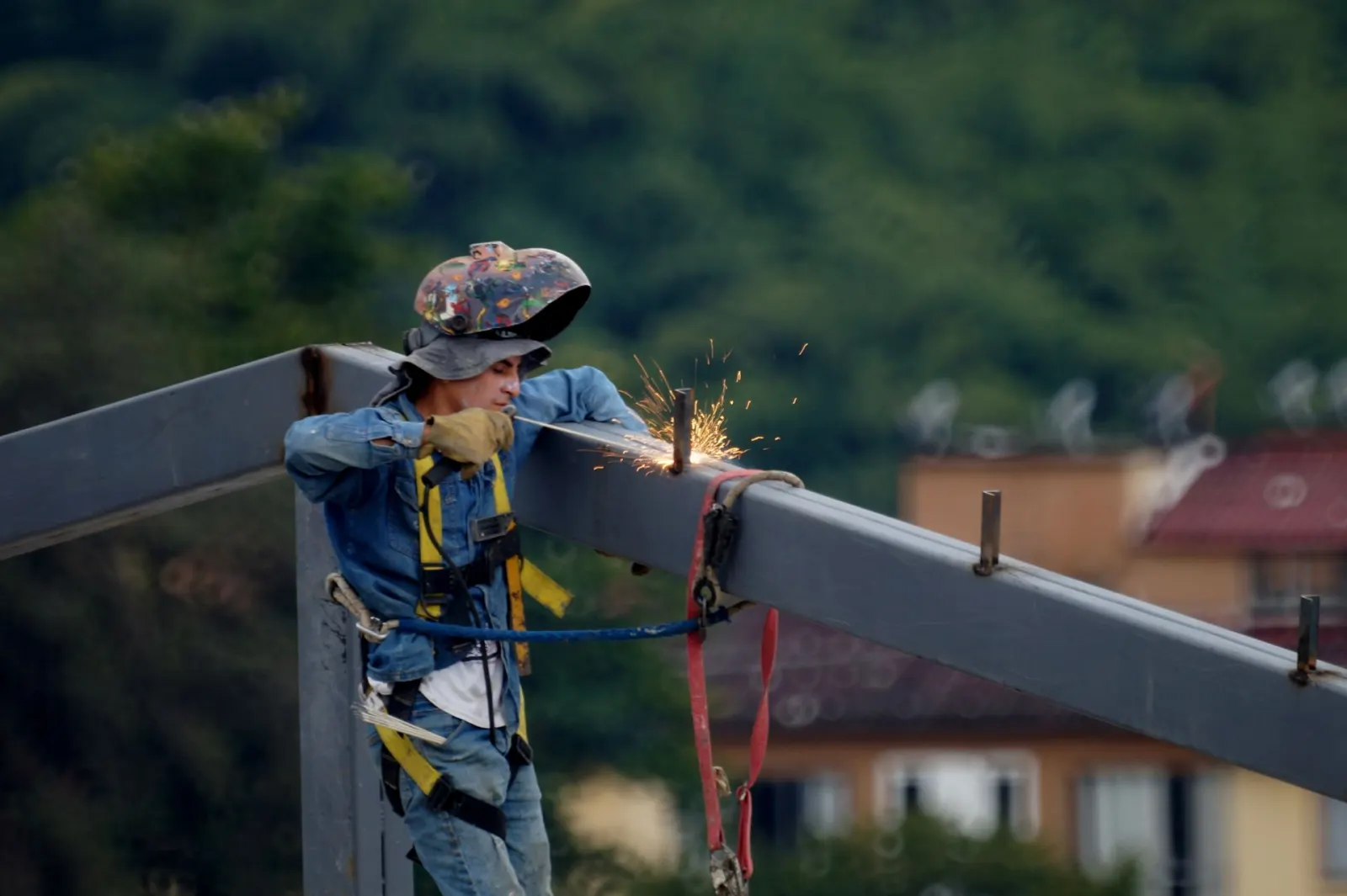 Worker welding a structural steel beam connection on site