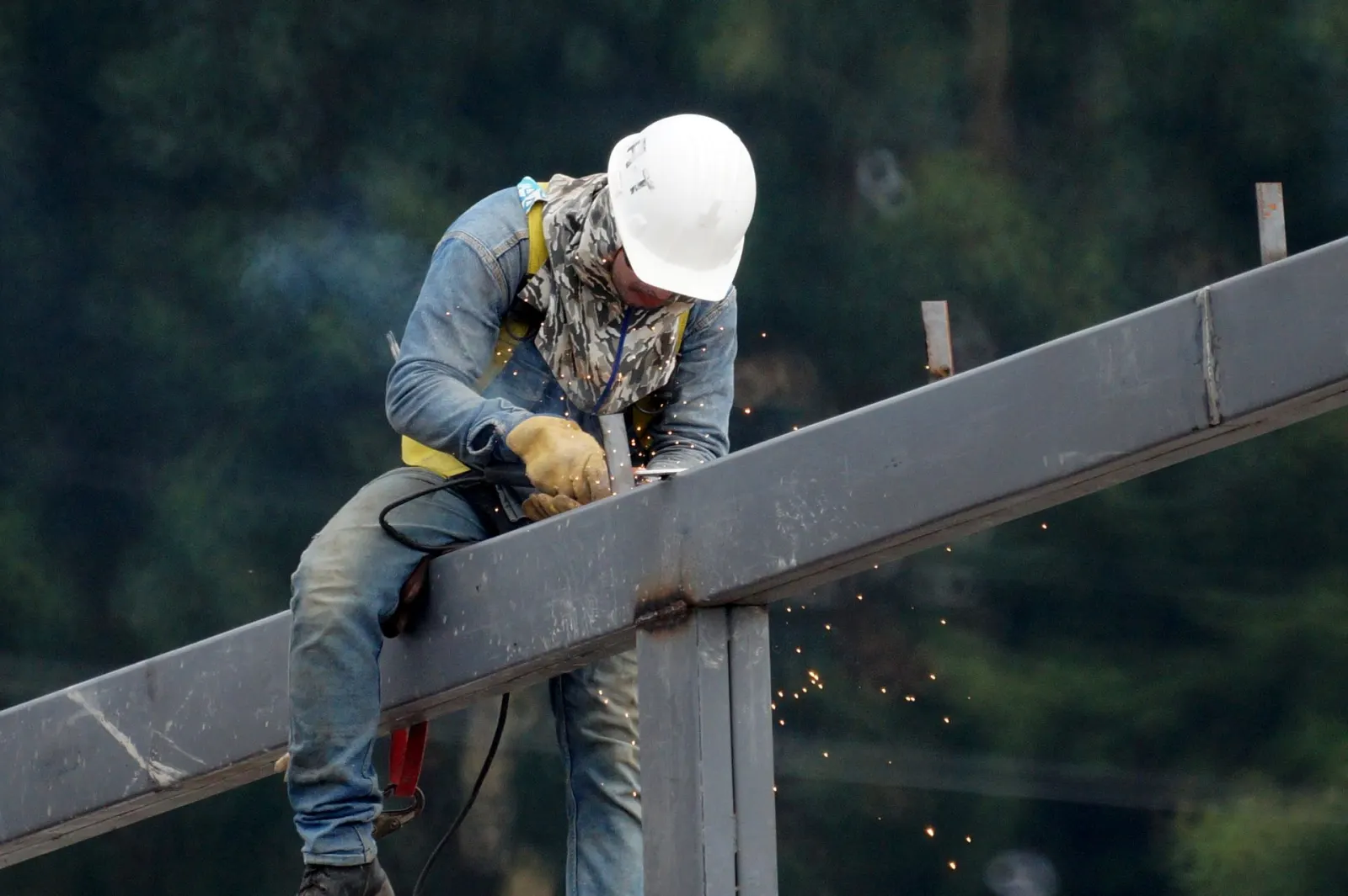 Construction worker welding a structural steel beam connection on site