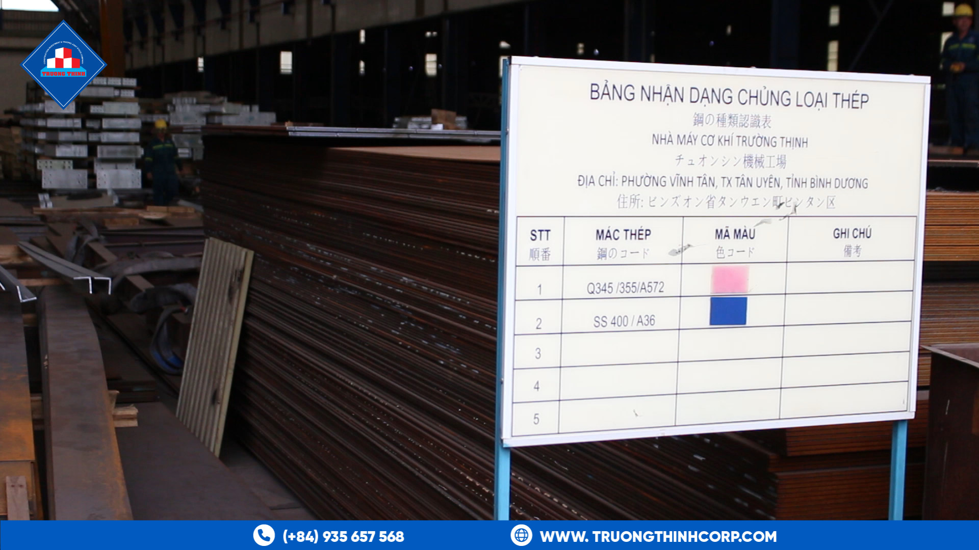Steel grade identification board beside stacked structural steel at the Truong Thinh factory yard