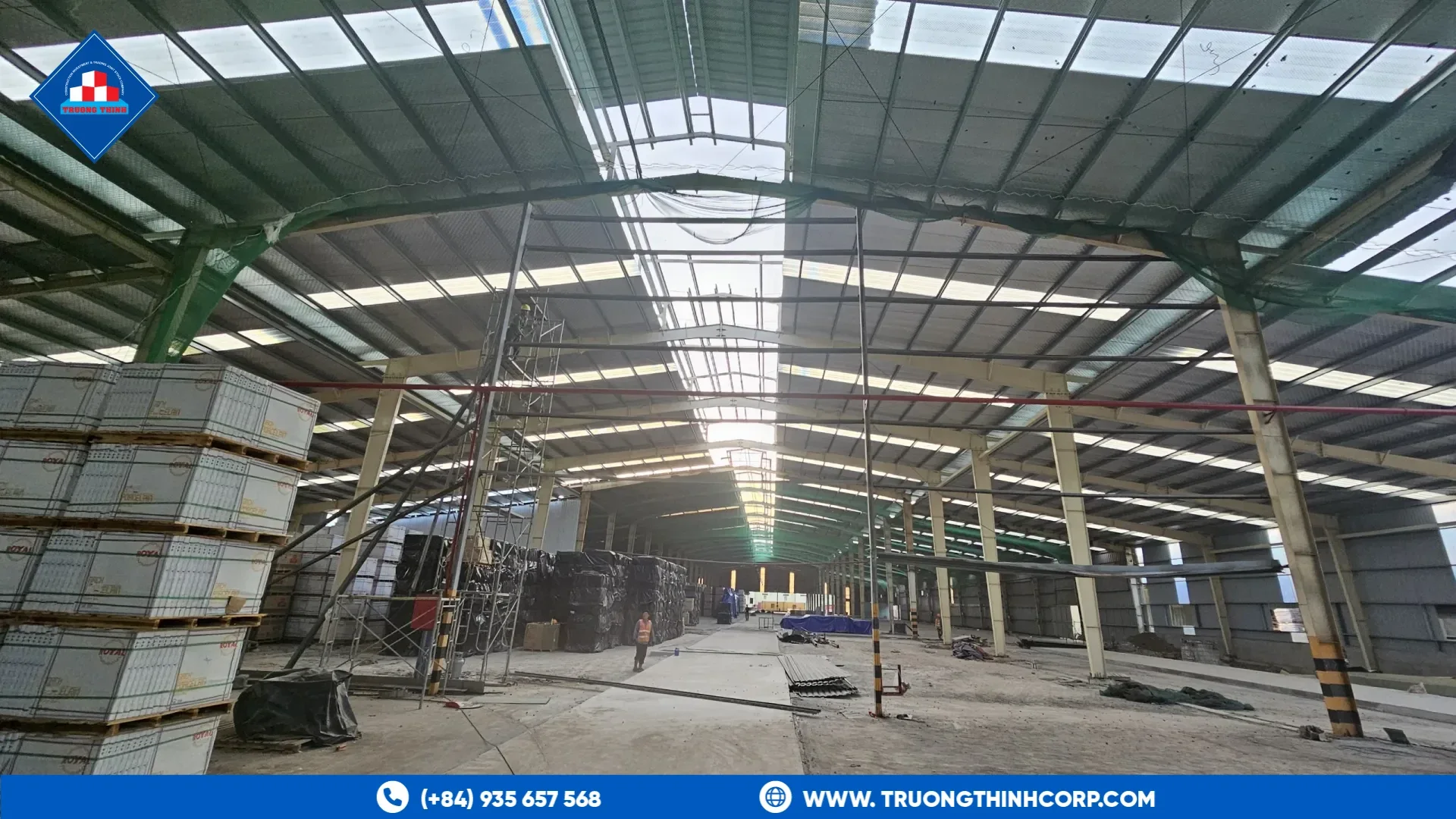 Interior of a steel-framed warehouse with columns, roof framing and stacked panels