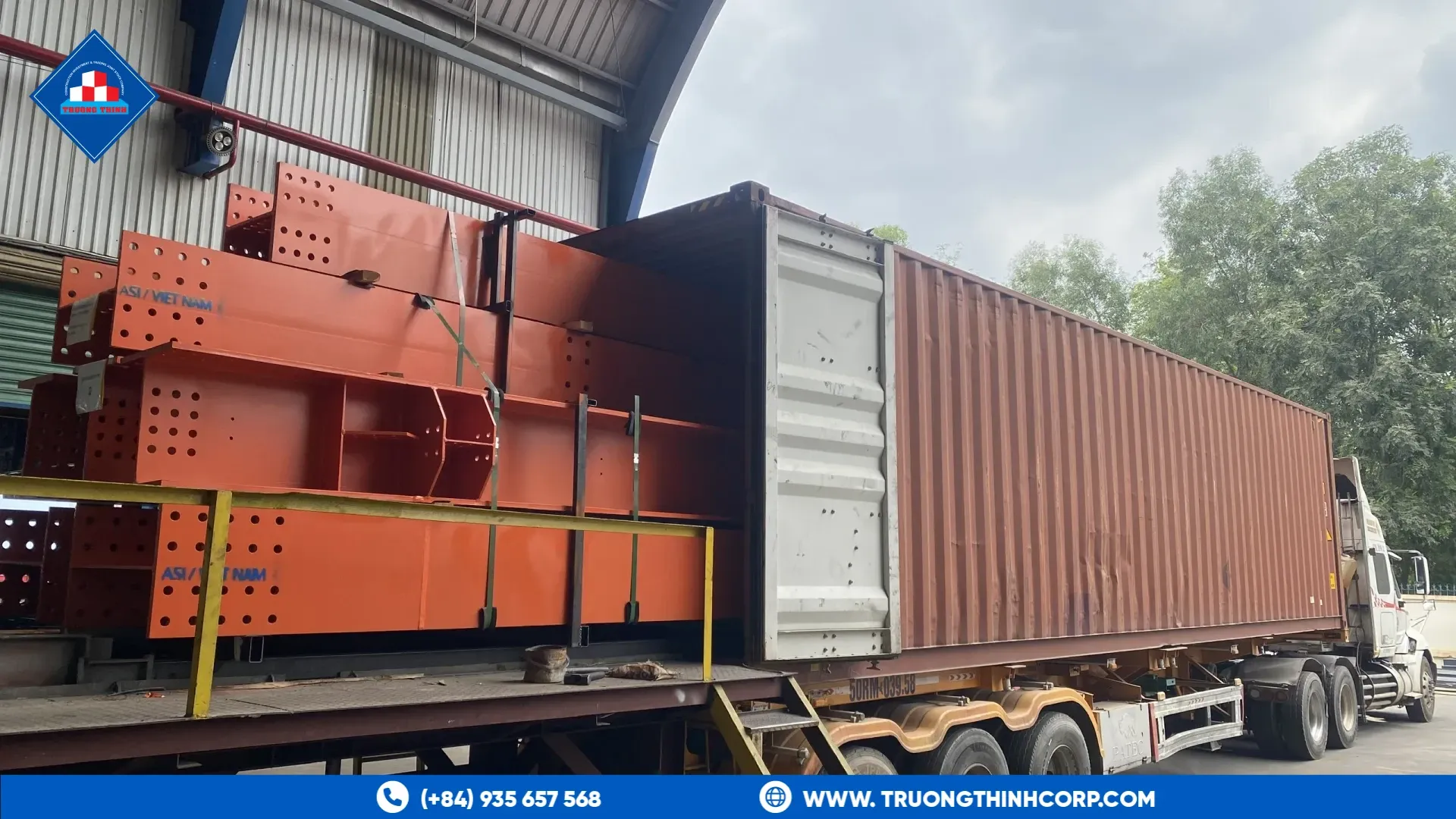 Orange-primed steel structure members loaded onto a container trailer for export from Truong Thinh Corp factory