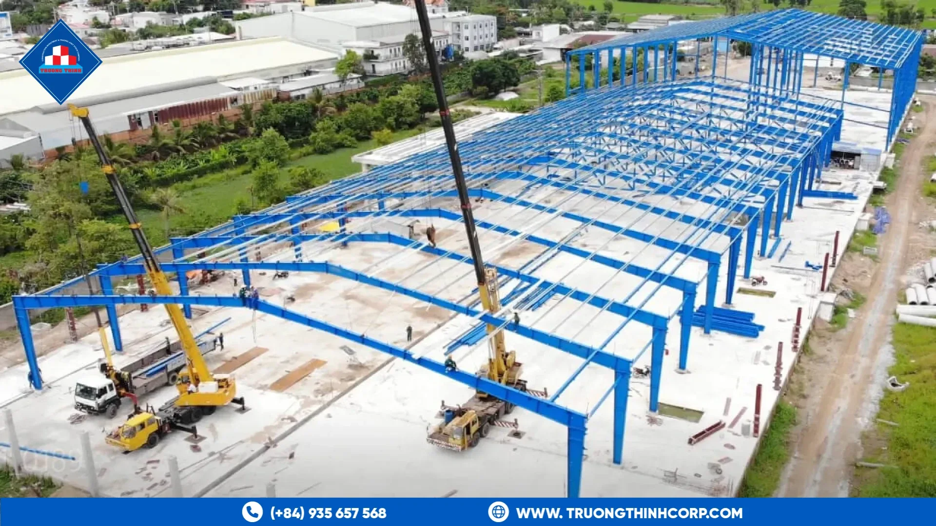 Blue steel portal frames under erection with a mobile crane on a concrete slab, Truong Thinh Corp project