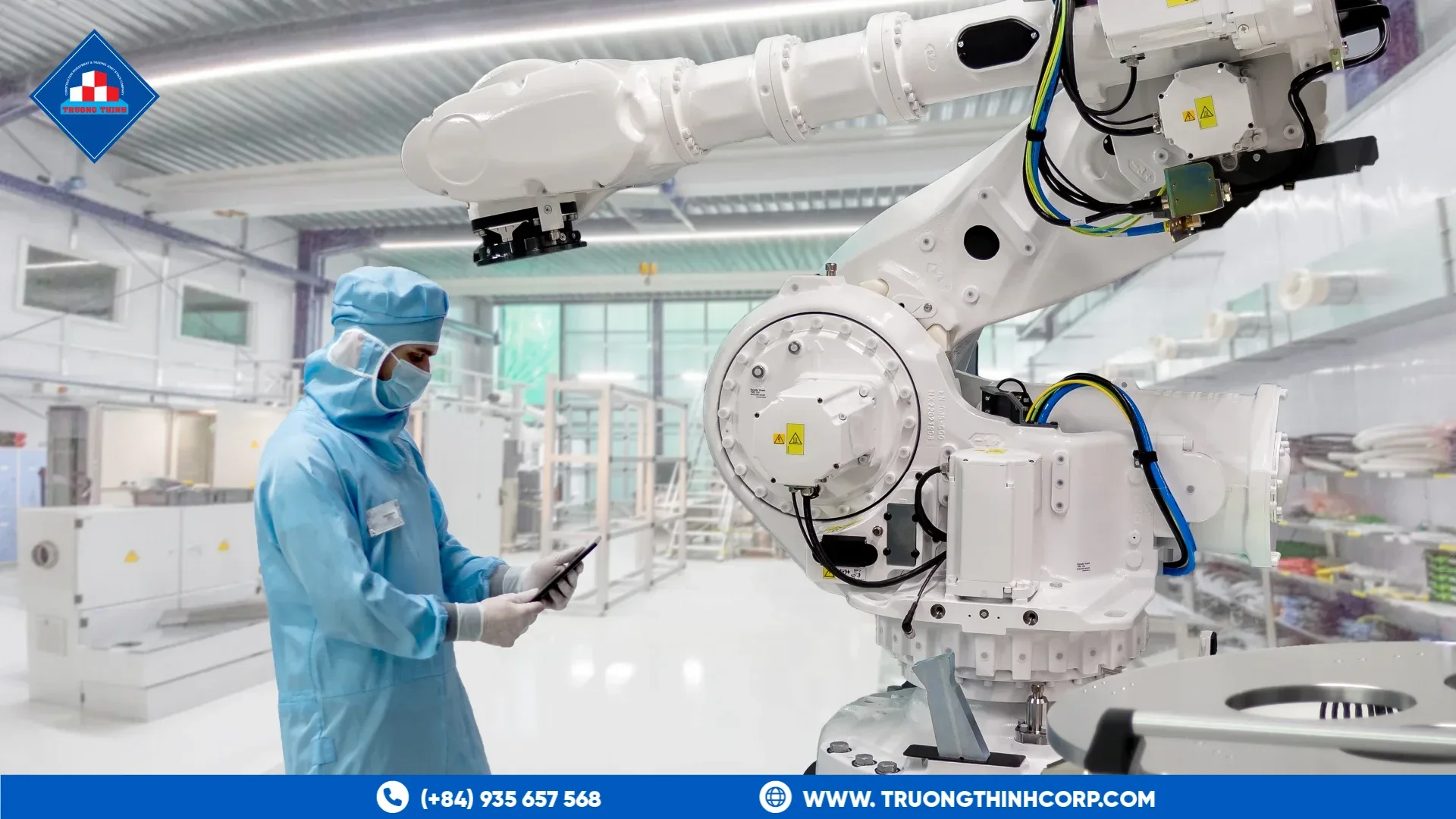 Operator in cleanroom garments beside an automation robot in a clean production hall